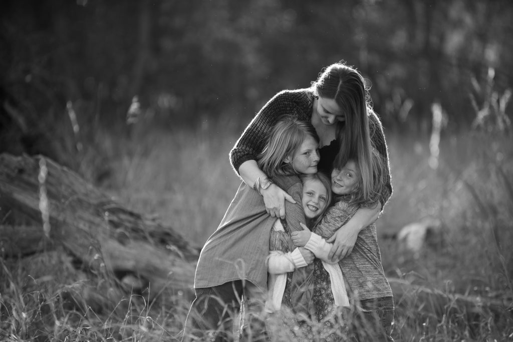 family hugging along the poudre river in fort collins, colorado