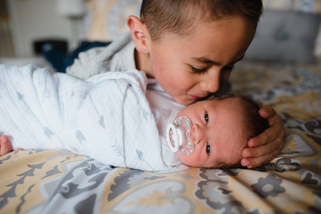Brother whispering in baby's ear.