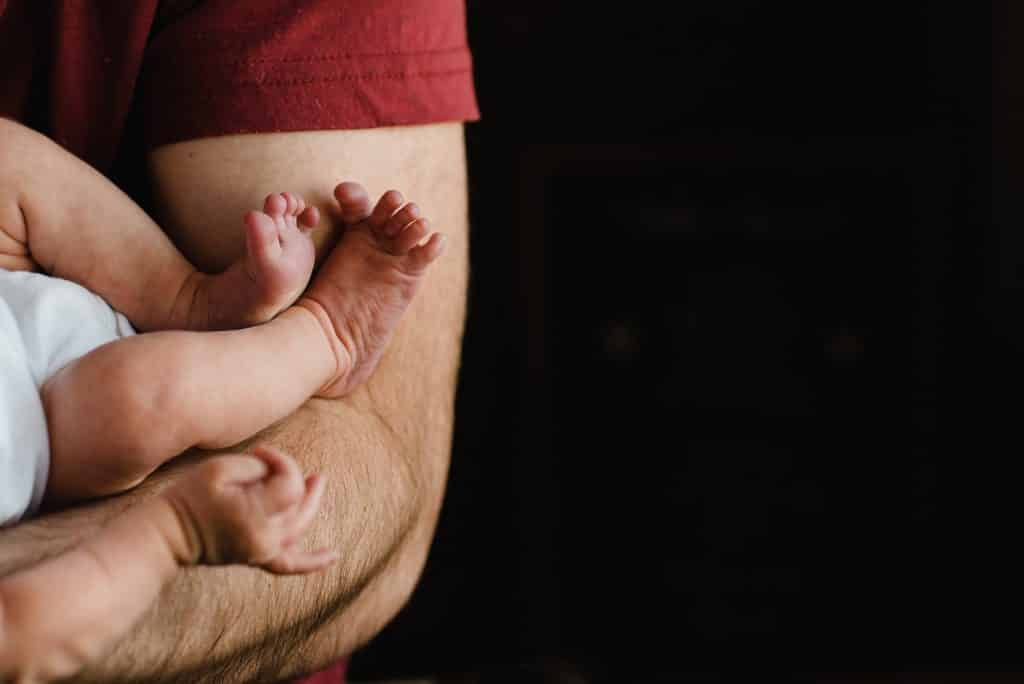Baby feet next to dad's arms