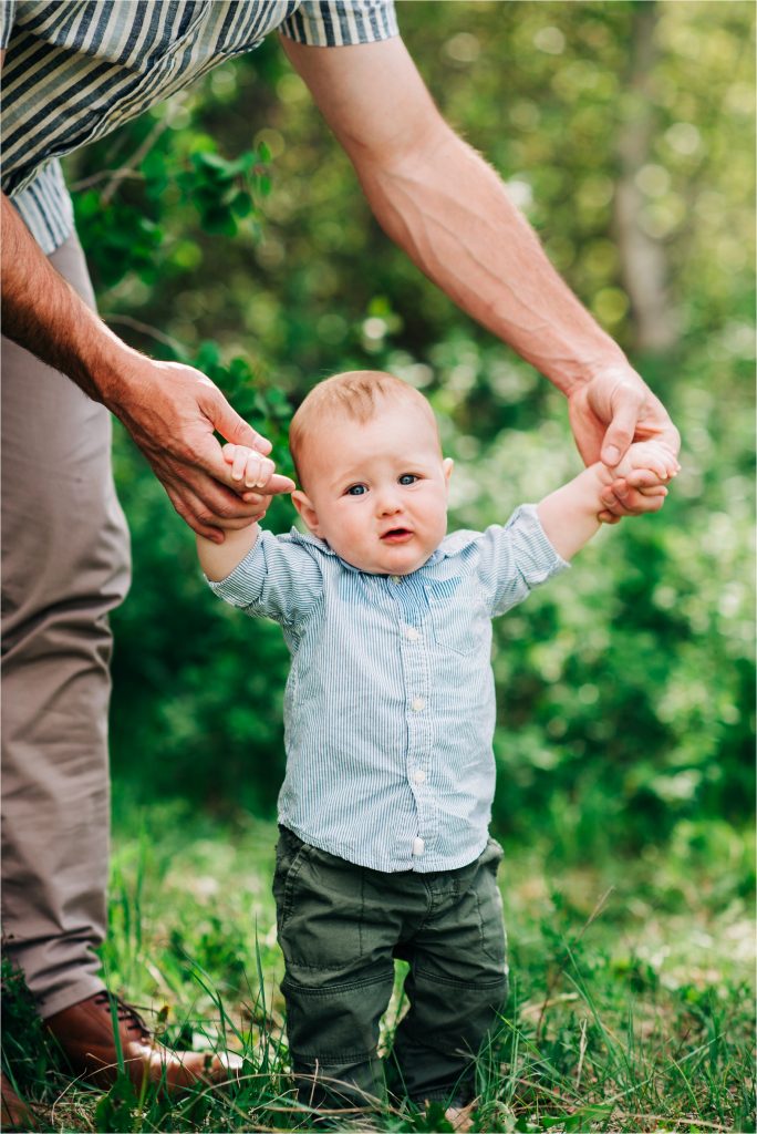 Baby walking with dad during six month old photoshoot in Wyoming.