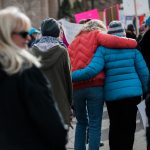 women hugging as they march down capital ave in cheyenne wy