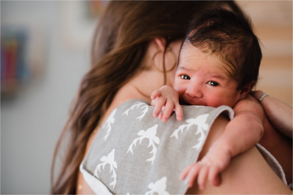 Baby on mom's shoulder during lifestyle newborn photography session.