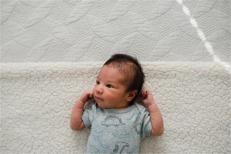 Baby looking at window during lifestyle newborn photography session.