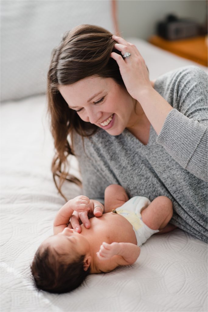 Mom and baby on bed during lifestyle newborn photography session.