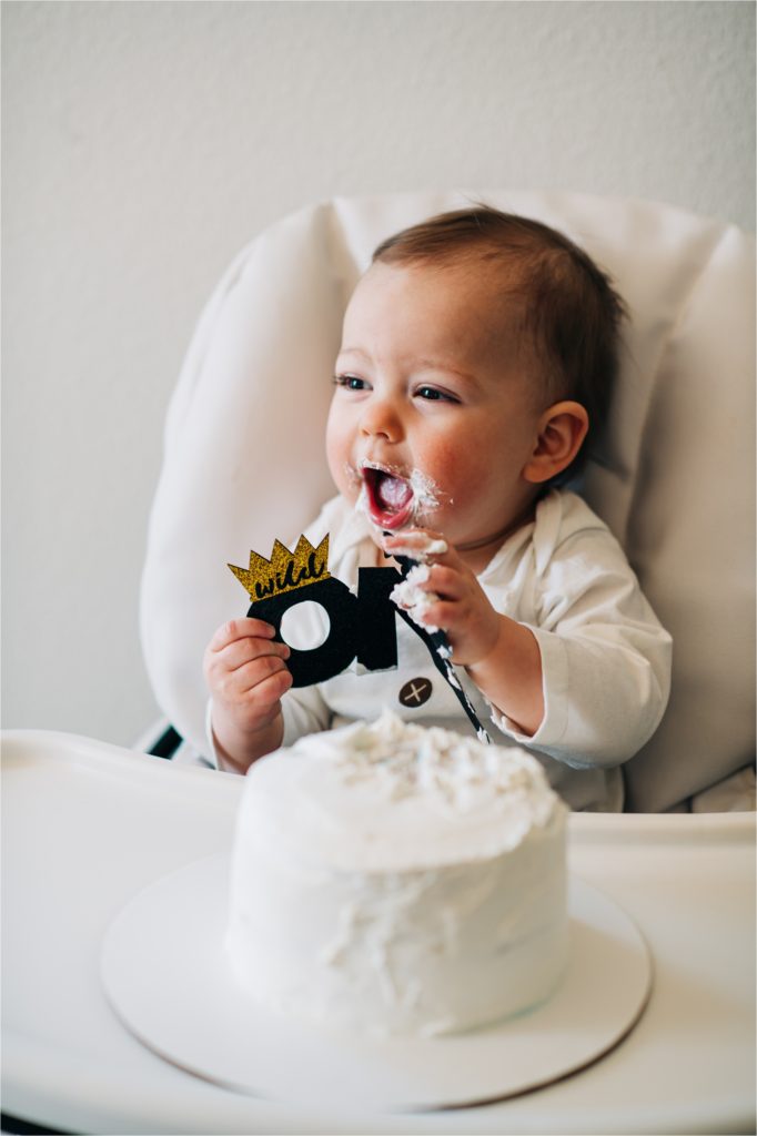 Baby squealing while eating cake in highchair.