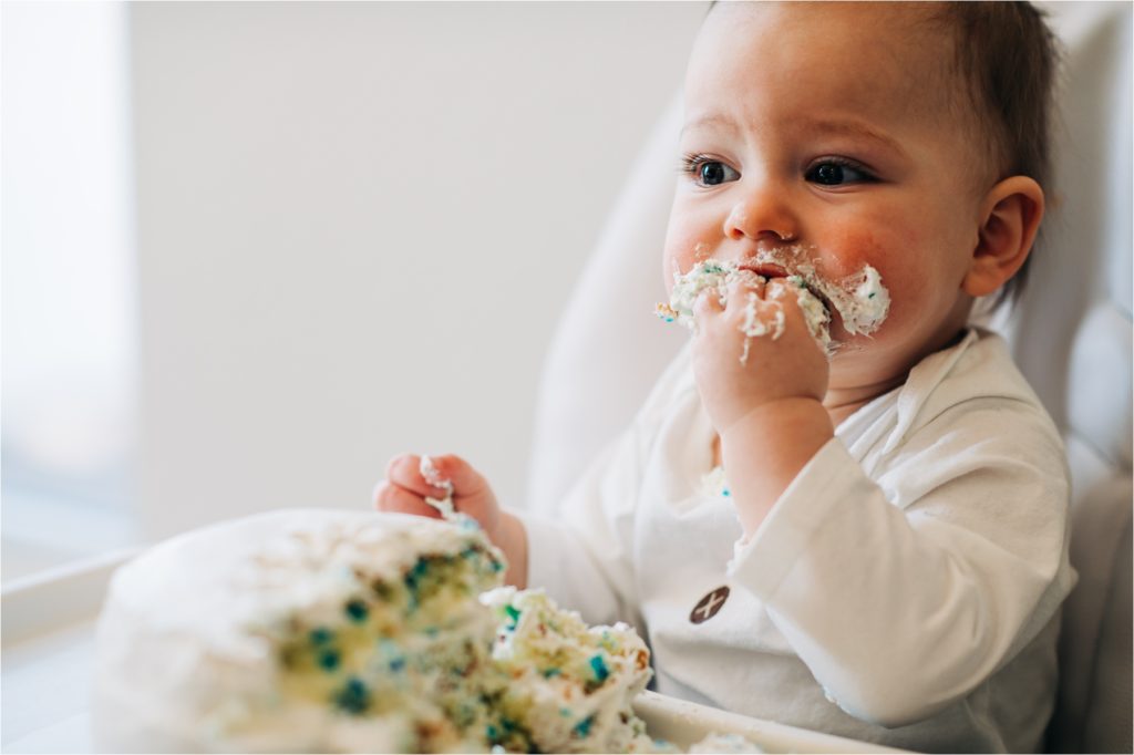 Baby happily shoving cake in his mouth.