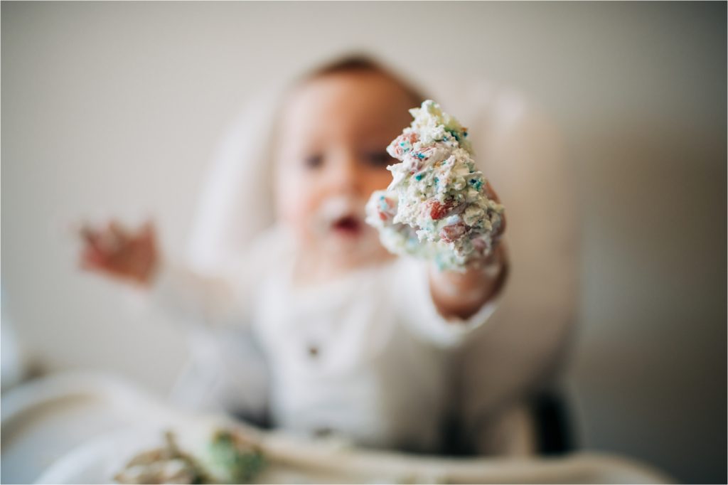 Baby reaching for camera with cake on his hands.