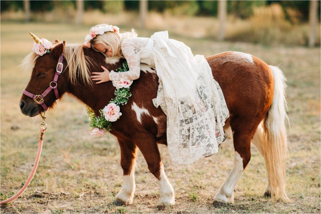 Girl hugging pony.