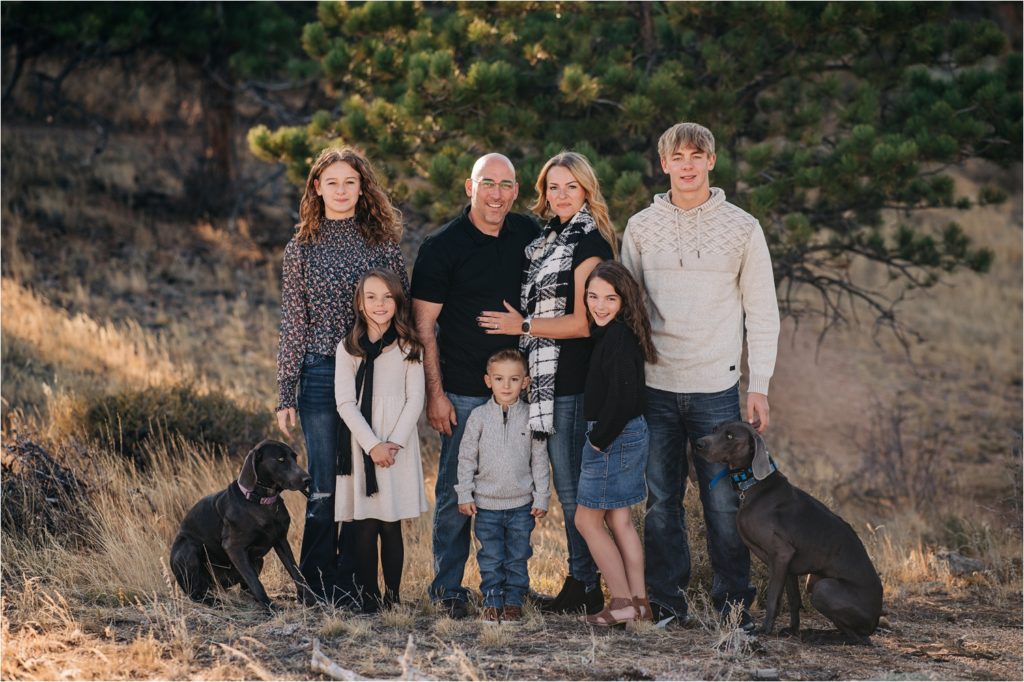Family with two dogs smiling at the camera during family photos.