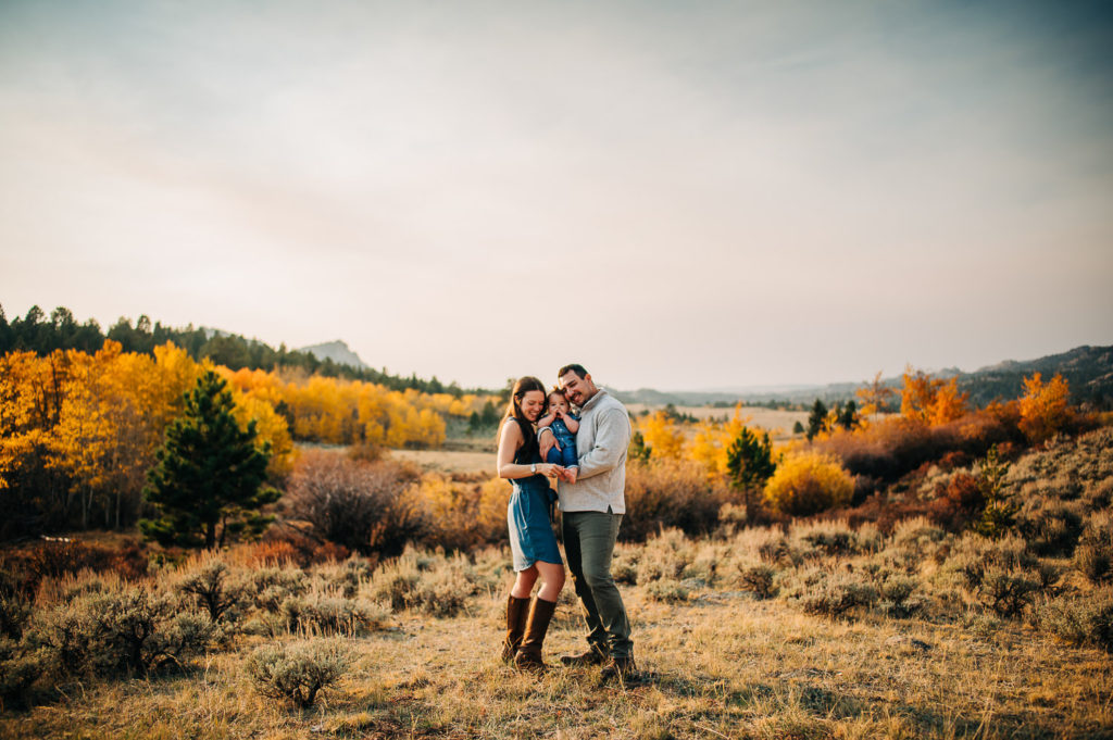 Couple snuggling baby during fall in the Medicine Bow National Forest in Wyoming.