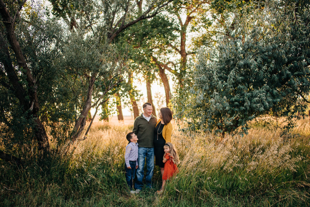 Family standing and chatting near russian olive trees.
