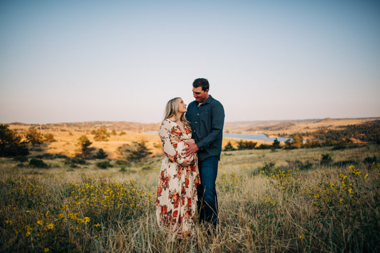 Couple smiling at each other while hugging during Cheyenne maternity photographer session.