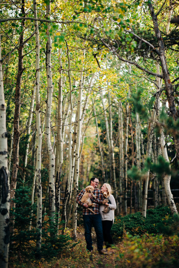 Couple holds their puppies in an aspen grove at Vedauwoo Recreation Area.